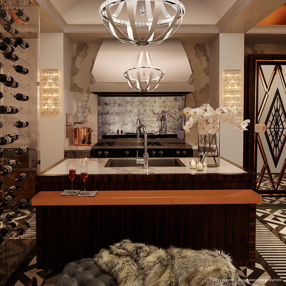 The Tabernash gallery3 features a marble island, built-in stove, chandelier lighting, wine rack, modern decor, patterned floor, and a fur throw on the bench. Two glasses of red wine rest on the counter.