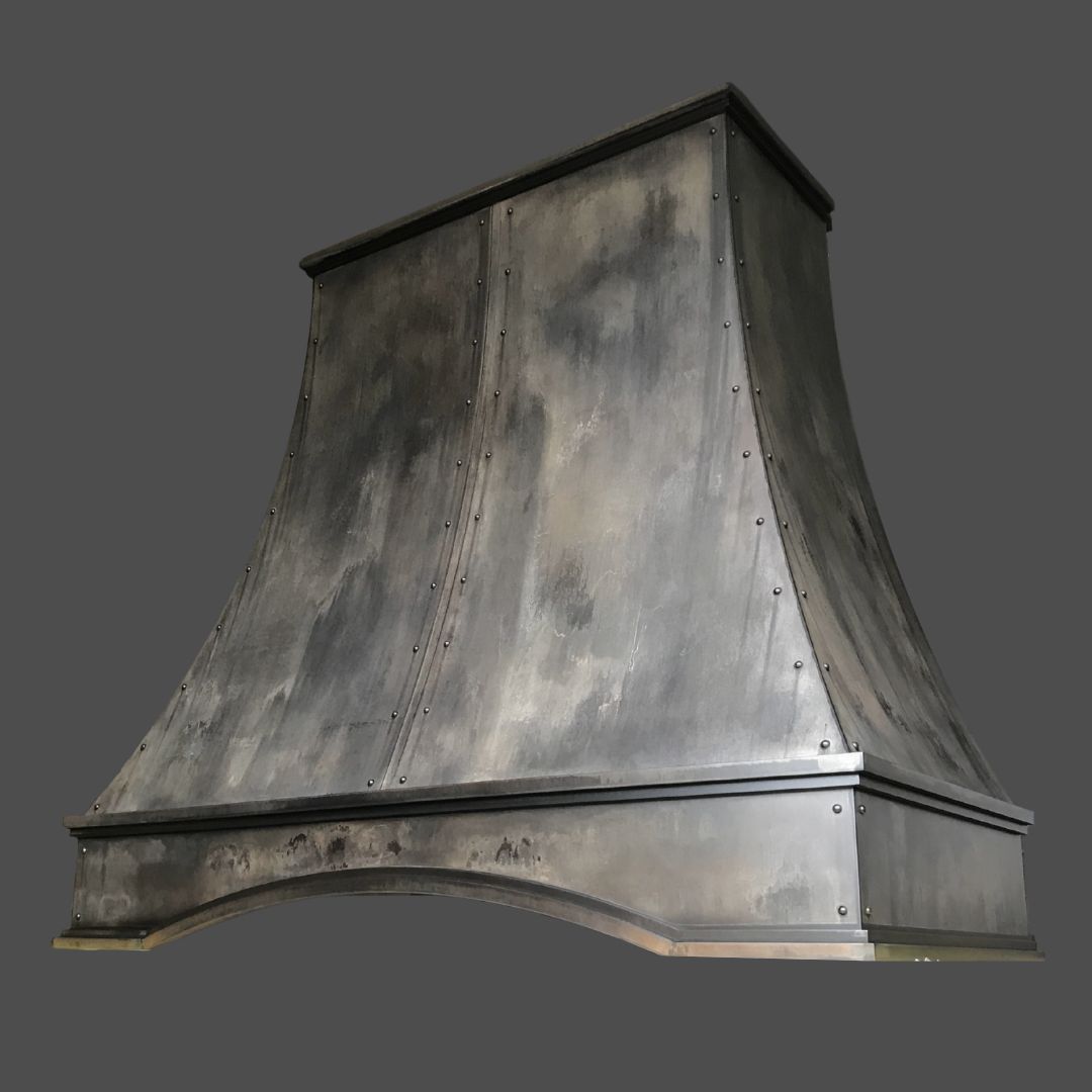 The Vintage Reclaimed 1 is a large, dark metal kitchen range hood featuring a slightly curved shape and visible rivets along the seams, displayed against a plain gray background.