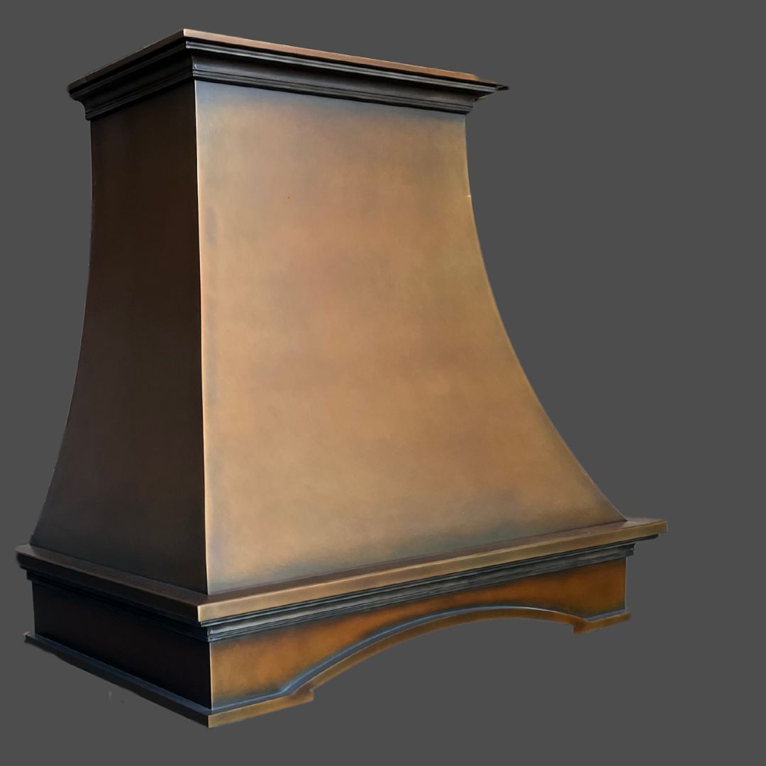 The Warm Foundry 2 is a large, metal range hood with a flared, trapezoidal shape and a bronze finish, displayed against a plain gray background.