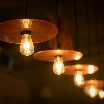 The Warm Foundry 2 pendant lights feature exposed bulbs within circular metal shades, casting a warm yellow glow that creates a cozy and inviting atmosphere.