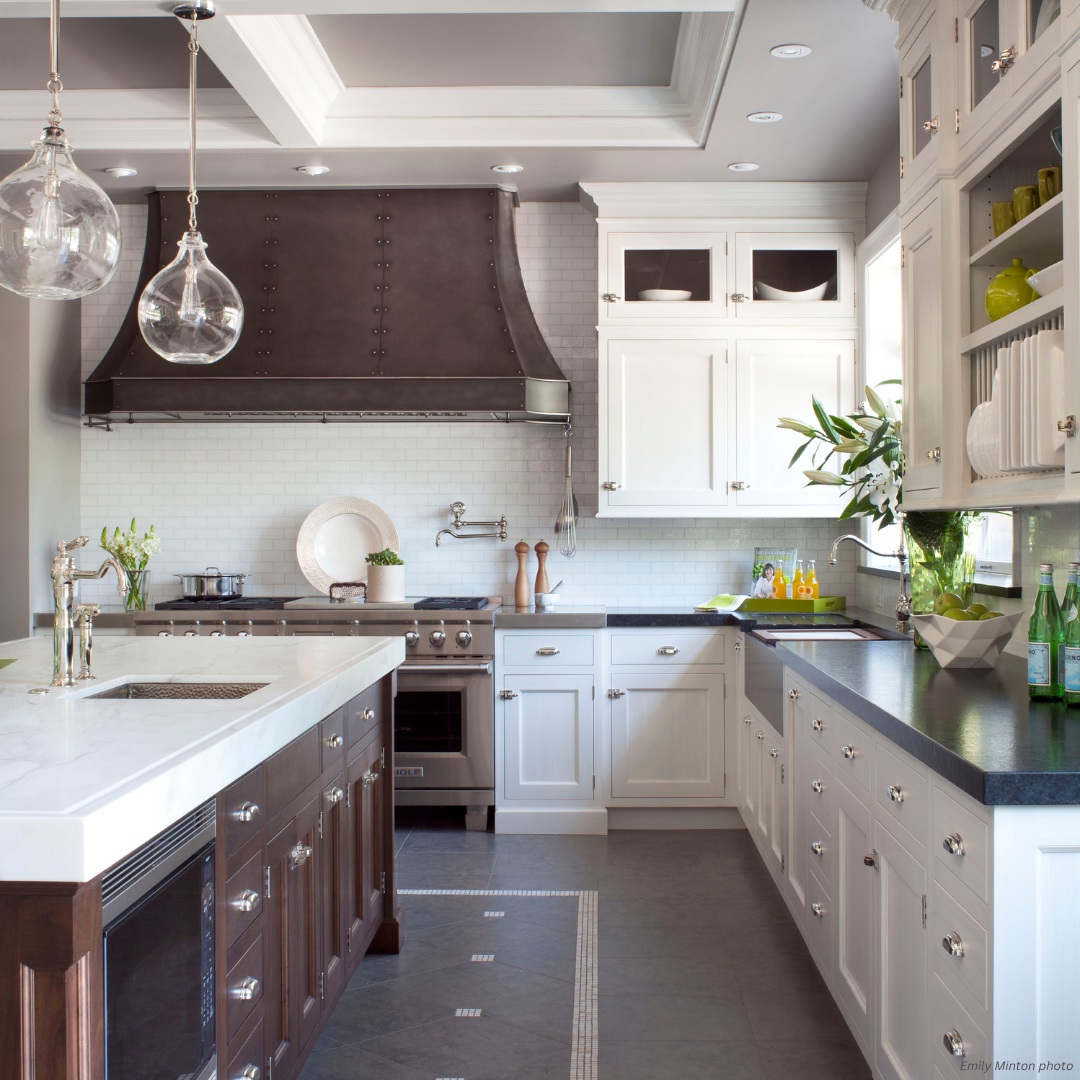 Winter Park gallery1 Winter Park gallery1 features a bright, modern kitchen with white cabinets, dark metal range hood, marble countertops, glass pendant lights, a kitchen island, and green plants by the right window.