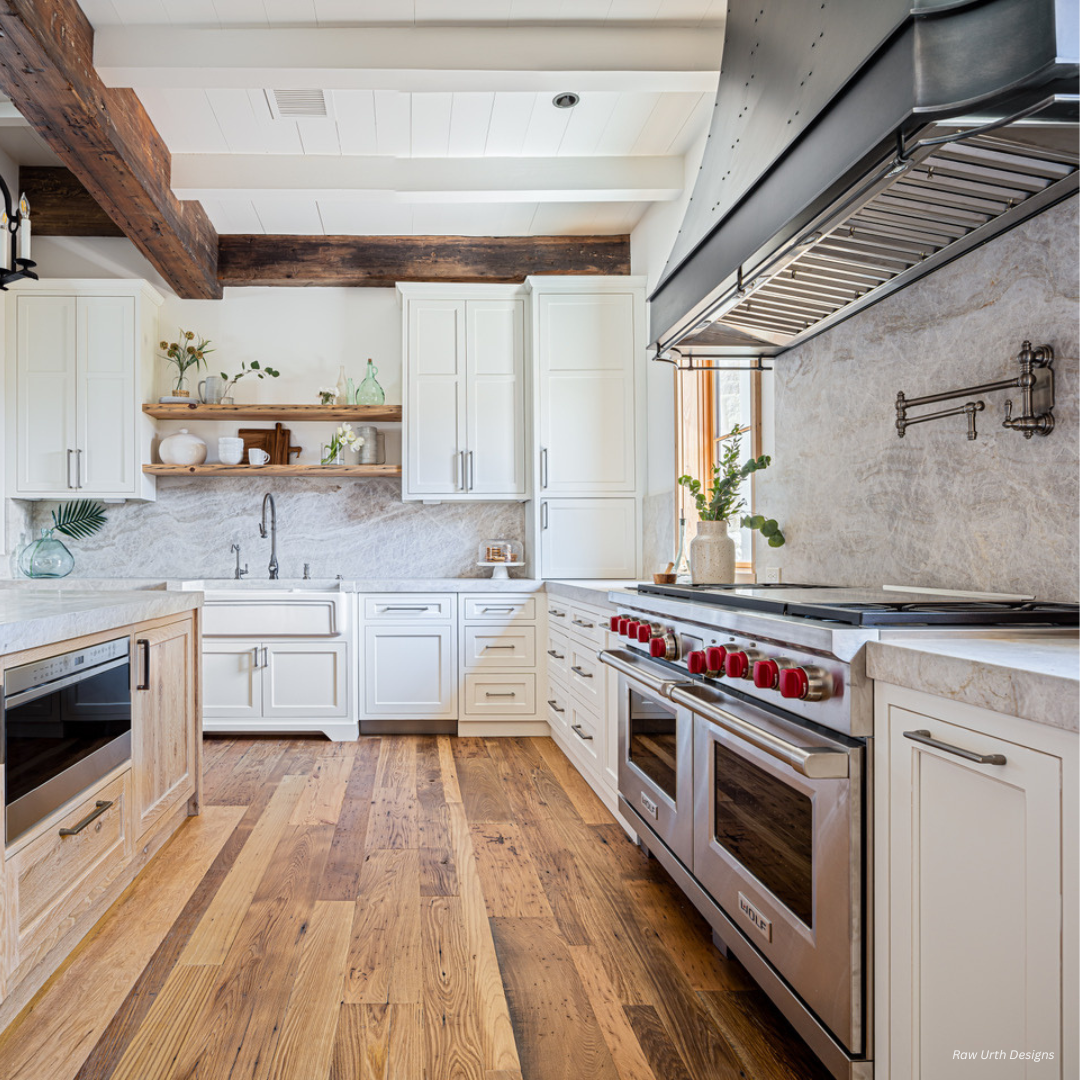 Winter Park gallery3 The Winter Park gallery3 kitchen features white cabinets, stainless steel appliances, marble counters and backsplash, wood beams, open shelving with plants, wide plank flooring, and ample sunlight from a large window.