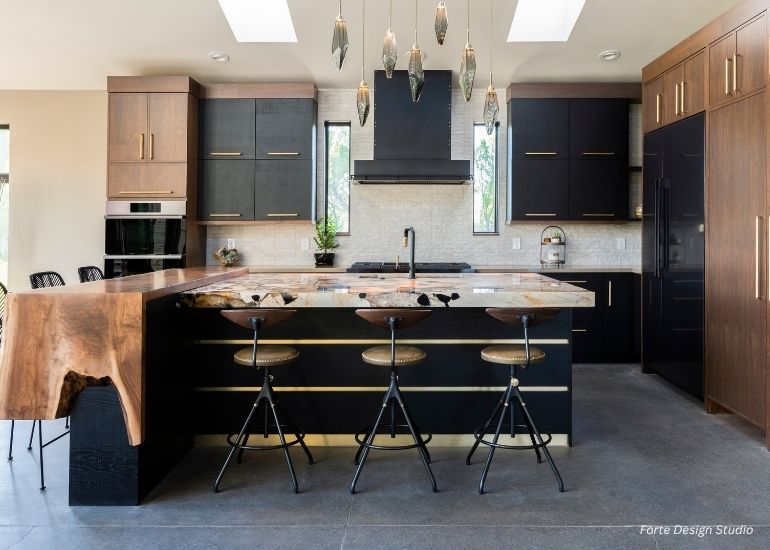 Modern kitchen featuring ru-custom-leadville black and wood cabinets, a distinct live-edge wood countertop island with three industrial-style stools, pendant lighting, stainless steel appliances, and large windows for natural light.
