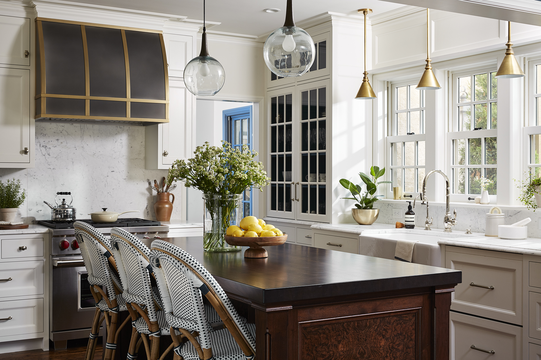 A kitchen with a large island and chairs, featuring the 3061 Aluminum RH Aspen Burnished Aluminum with Burnished Brass Straps by Welch Forsman Associates for a modern, elegant mixed metals accent.