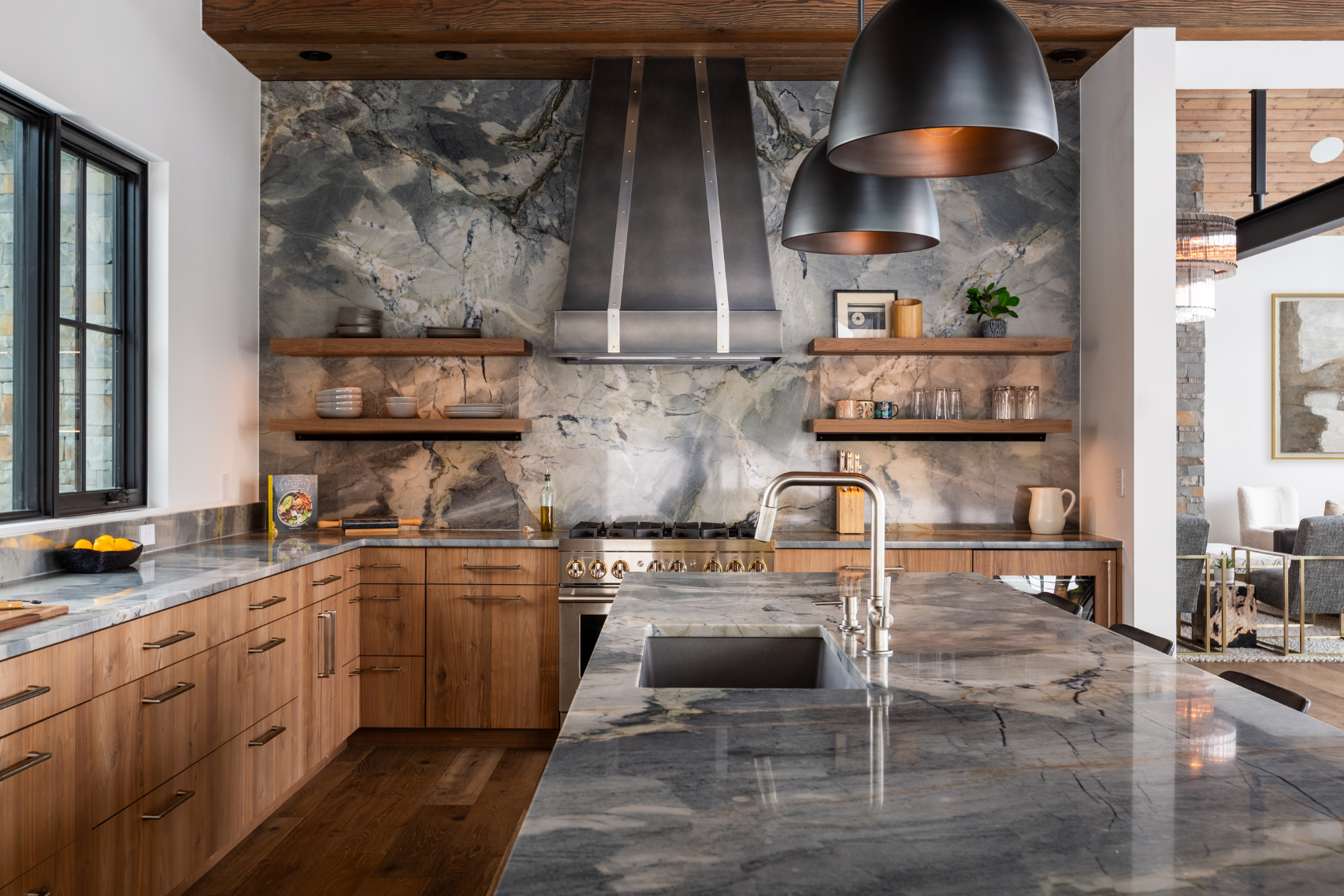 Sleek kitchen features wood cabinets, marble counters and backsplash, metal range hood, open shelving with dishes, pendant lights, and a spacious island with built-in sink and stylish faucet. Highlighted product: 11.