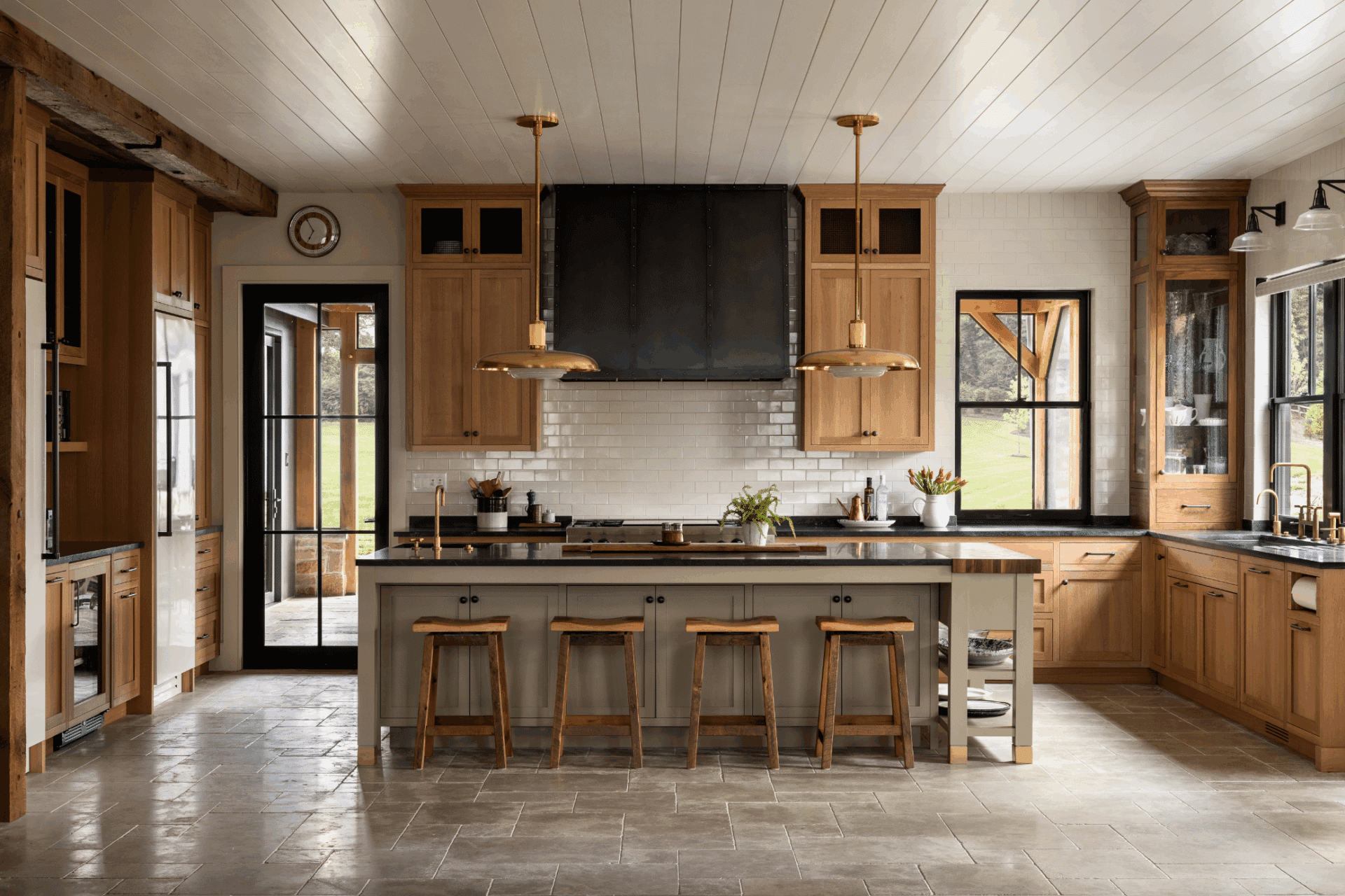 The 3 features a spacious farmhouse kitchen with wood cabinets, black range hood, white subway tile backsplash, central island seating four, pendant lighting, and large windows for ample natural light.