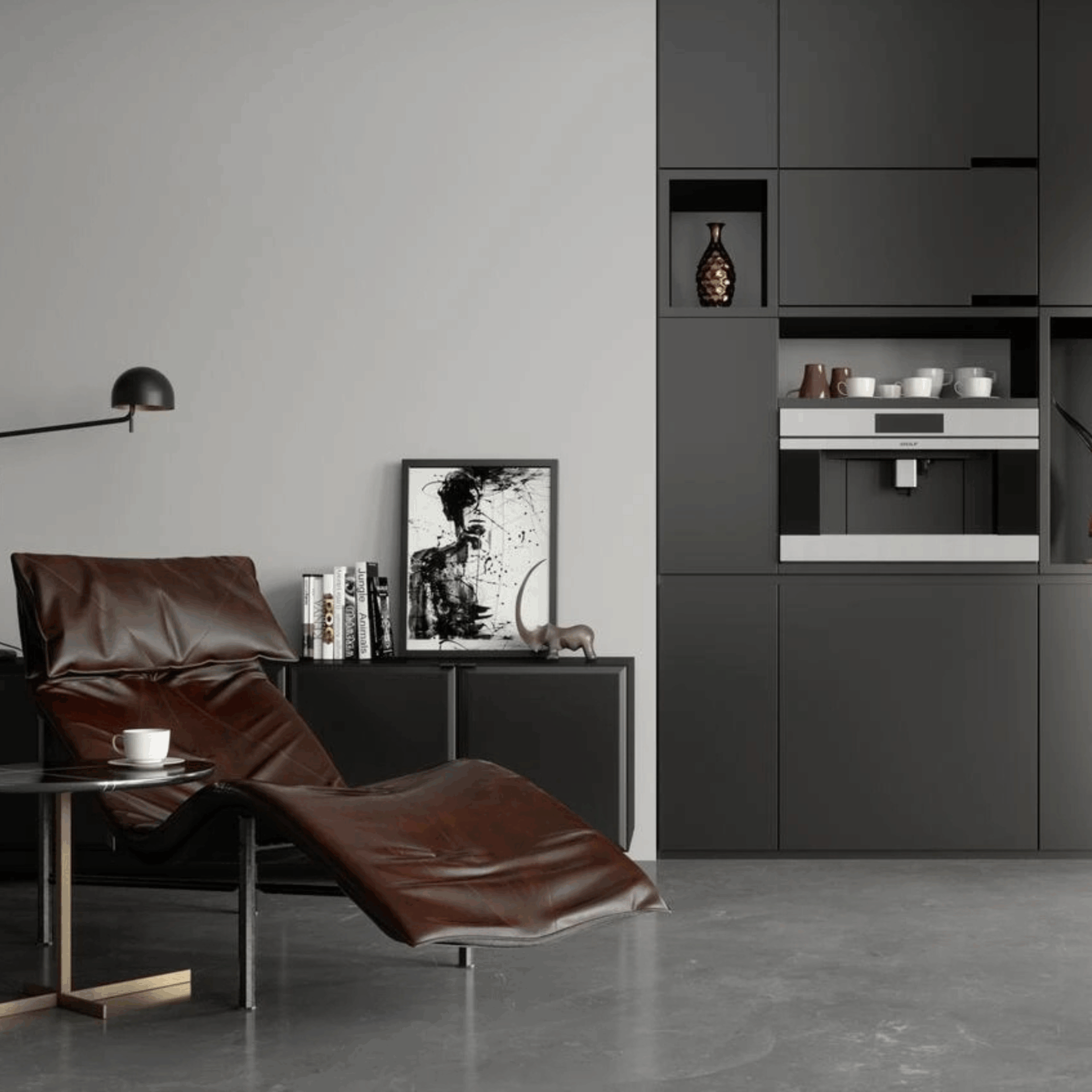 A modern living space features a brown leather lounge chair, side table with a cup, Built in Espresso coffee machine set in matte black cabinets, abstract art, and minimalist decor on gray floors and walls.